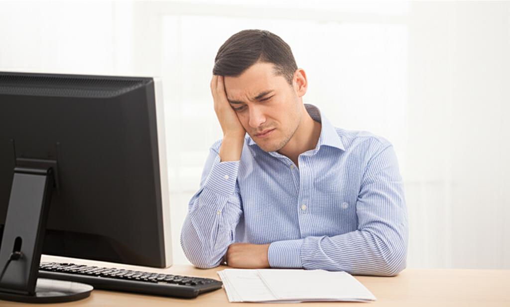 man sitting at desk looking tired due to frequent urination, low energy, frustrated expression, office environment